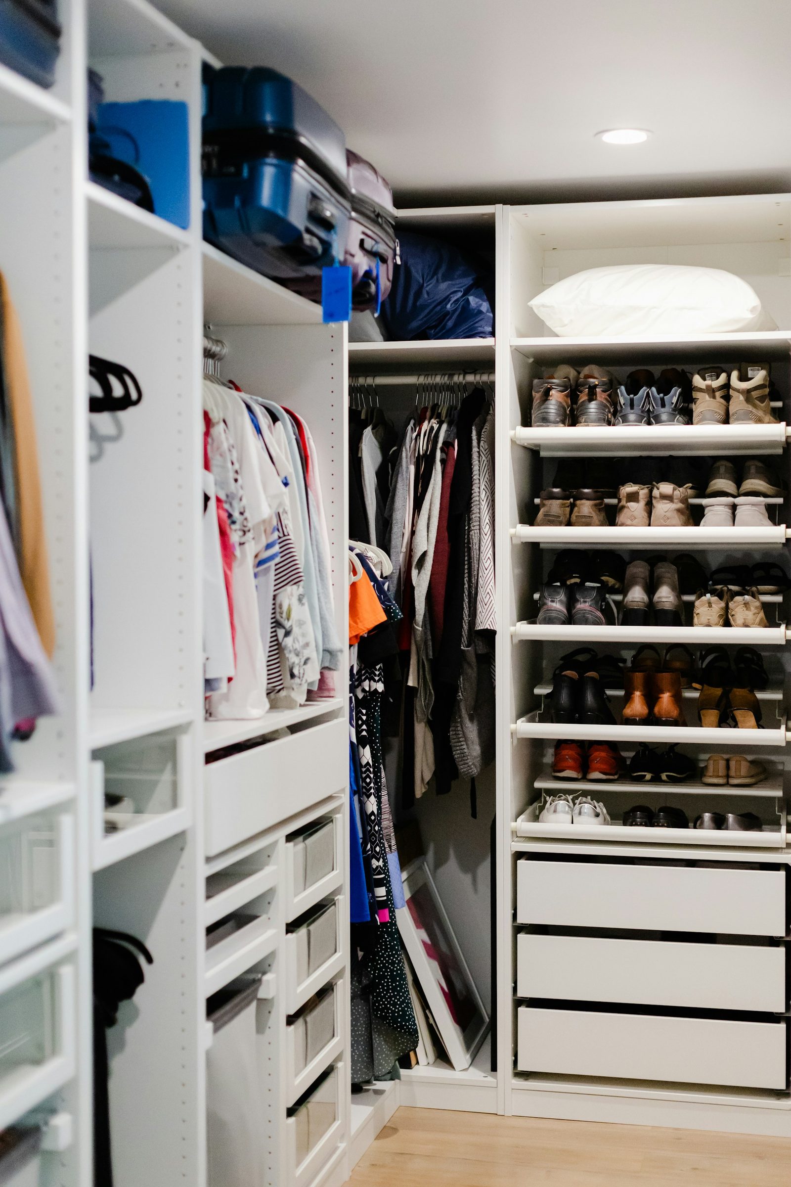 Organized reach-in closet with drawers, double hanging rods, shelves, and shoes